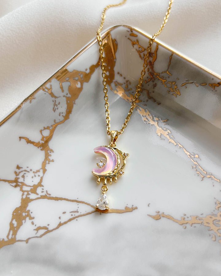 Collier croissant de lune présenté sur une assiette blanche et doré