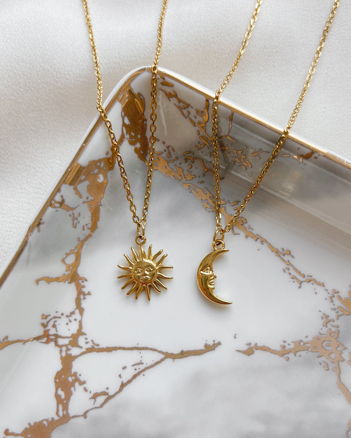 Pendentifs soleil et lune exposés sur une assiette blanche et dorée