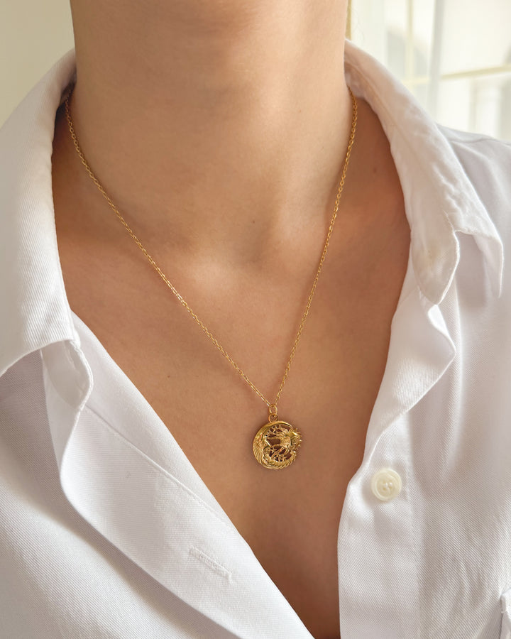 Pendentif soleil lune porté avec une chemise blanche pour un look céleste
