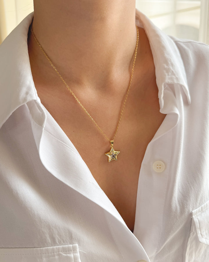 Collier étoile porté avec une chemise blanche pour un look élégant