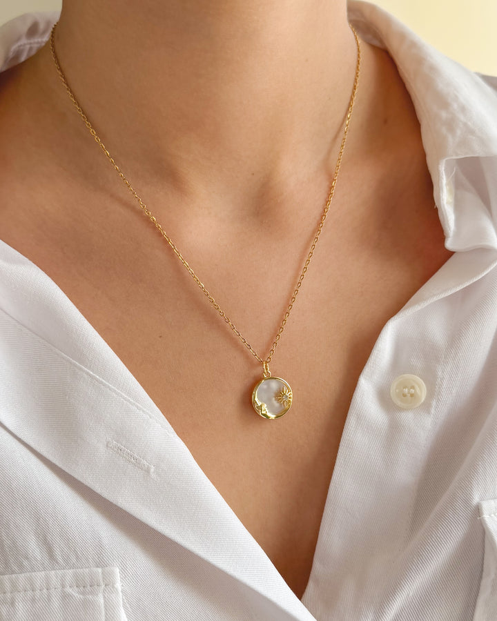 Duo de bijoux lune et soleil portés sur un cou de femme
