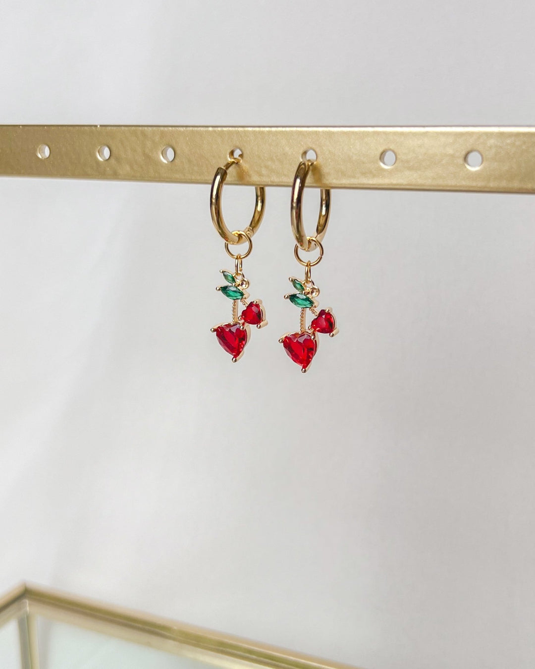 Vue rapprochée des boucles d'oreilles cerises sur fond neutre.