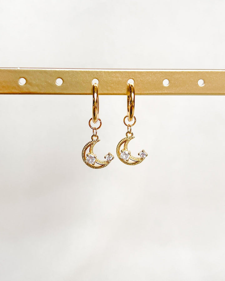 Boucles d'oreilles demi lune sur fond neutre.