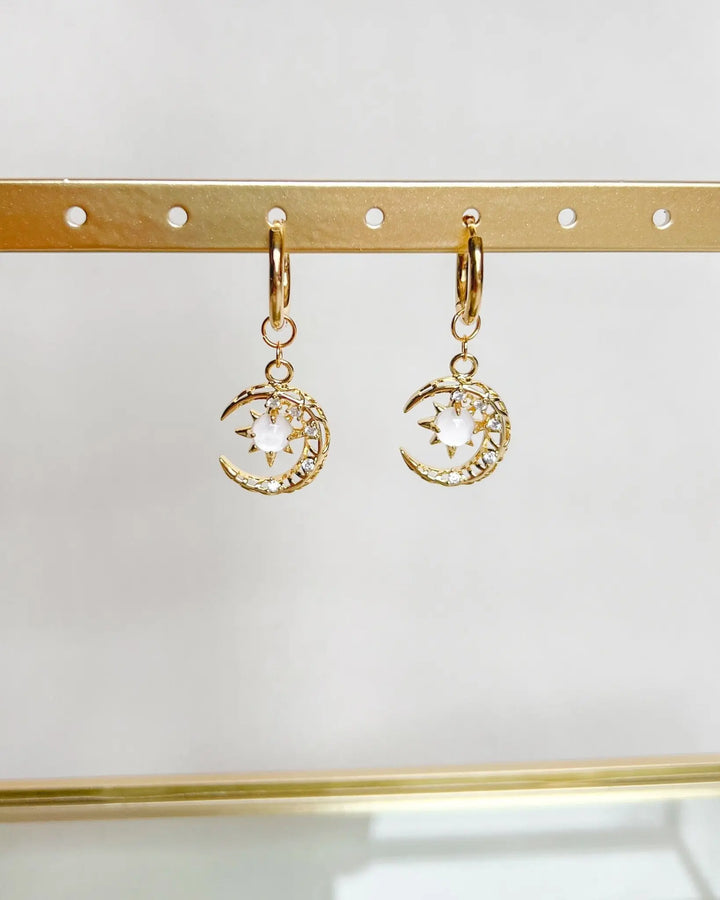 Boucles d'oreilles lune sur fond neutre.