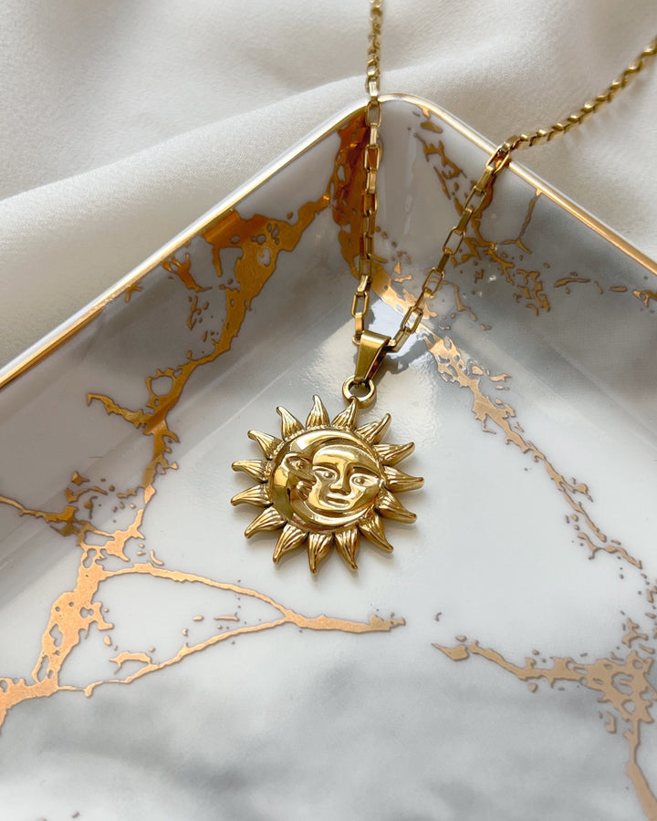 Collier solaire posé sur une assiette blanche et dorée.