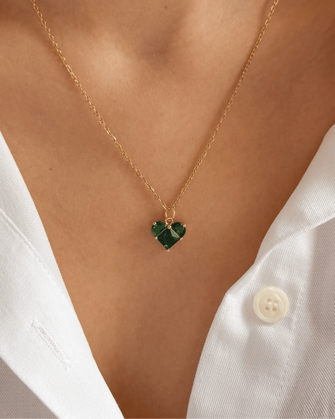 Collier cœur vert porté sur un cou de femme.