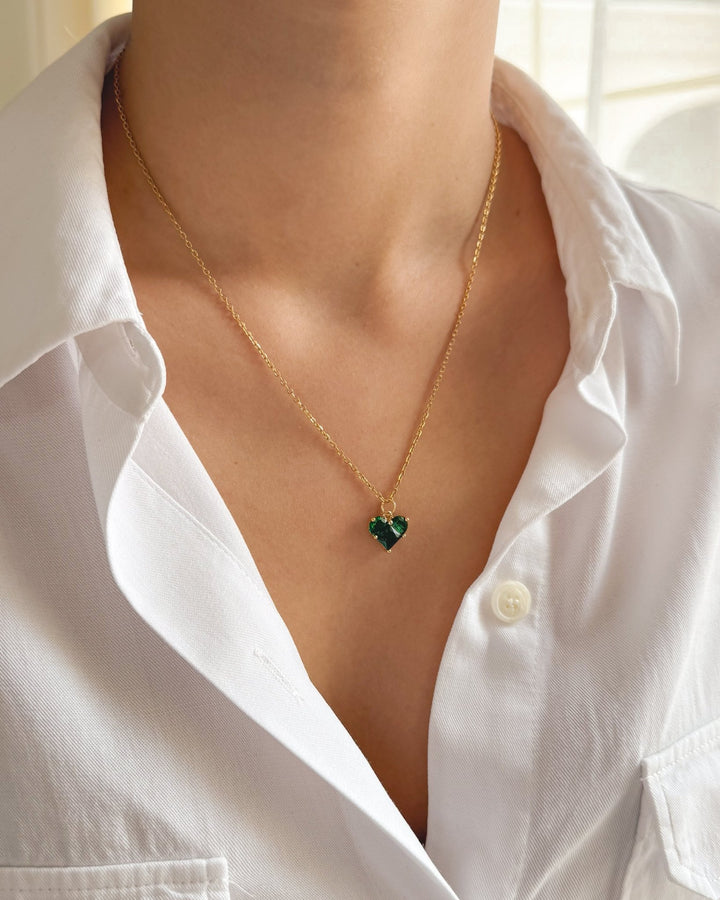 Collier cœur vert porté avec une tenue élégante.