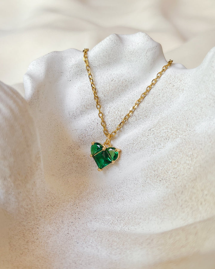 Collier cœur vert présenté sur une assiette en forme de coquillage.