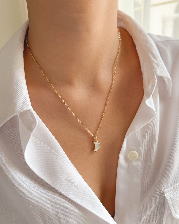 Pendentif lune porté avec une chemise blanche pour un style délicat.